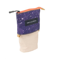 Small zip pouch with split design. Purple upper half features white stars and a constellation print with "COSMIC SURPLUS" label. Light beige lower half. Orange zipper with black and gold-toned accents.&nbsp;