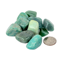 Blue-green stones with a quarter for scale on a white background