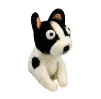 A small felt dog toy with a black and white patchwork design, featuring black ears with orange inner linings, white wool texture, and black spots, set against a plain white background.