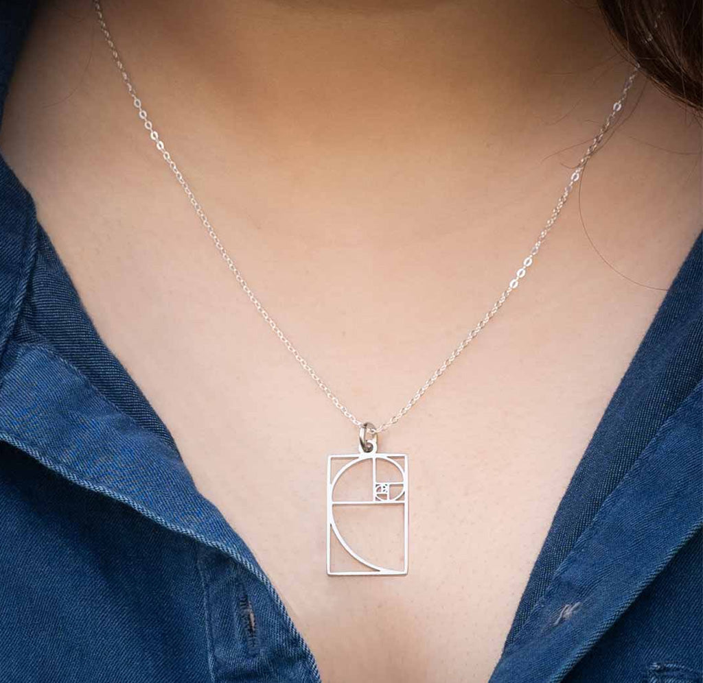 Silver necklace with a Fibonacci spiral pendant on a person's neck
