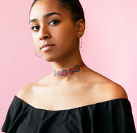 A person has multiple rainbow infinity tattoos placed around her neck. 