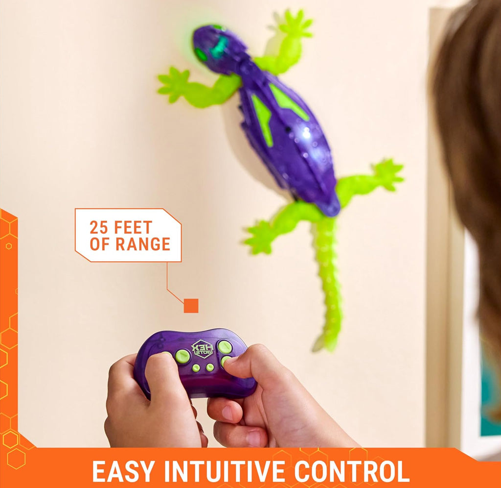 Purple and green toy gecko on a beige wall and a kid holding a remote controller. 