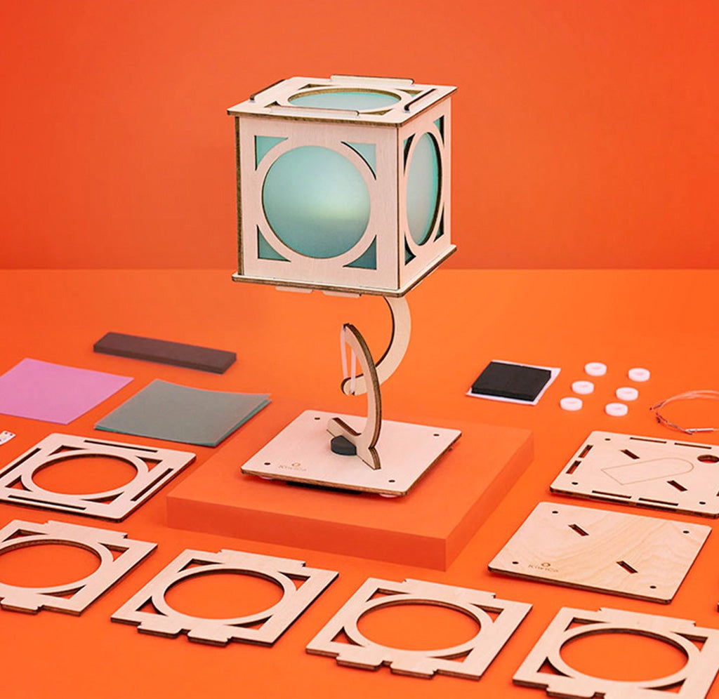 Wooden lantern on an orange background with pieces around it. 