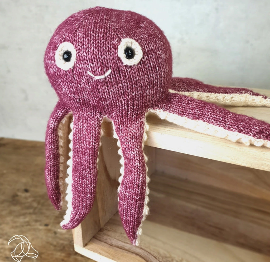 A knitted octopus sitting on a wooden crate.