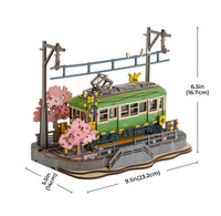 Model of a green train with cherry blossom trees and measurement details on a white background