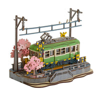 Model of a green train with cherry blossom trees on a white background