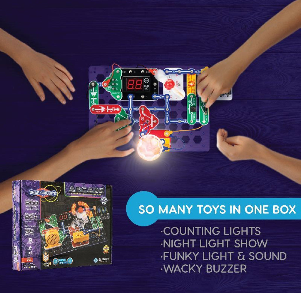 Hands playing with a toy circuit board set on a dark surface, with the toy box visible.