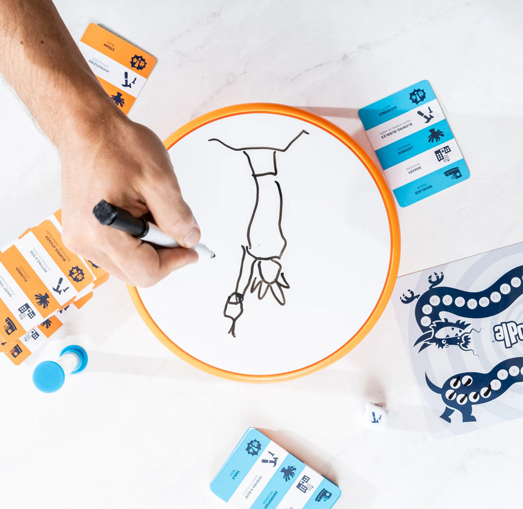 Person drawing on a circular white board with cards and markers around