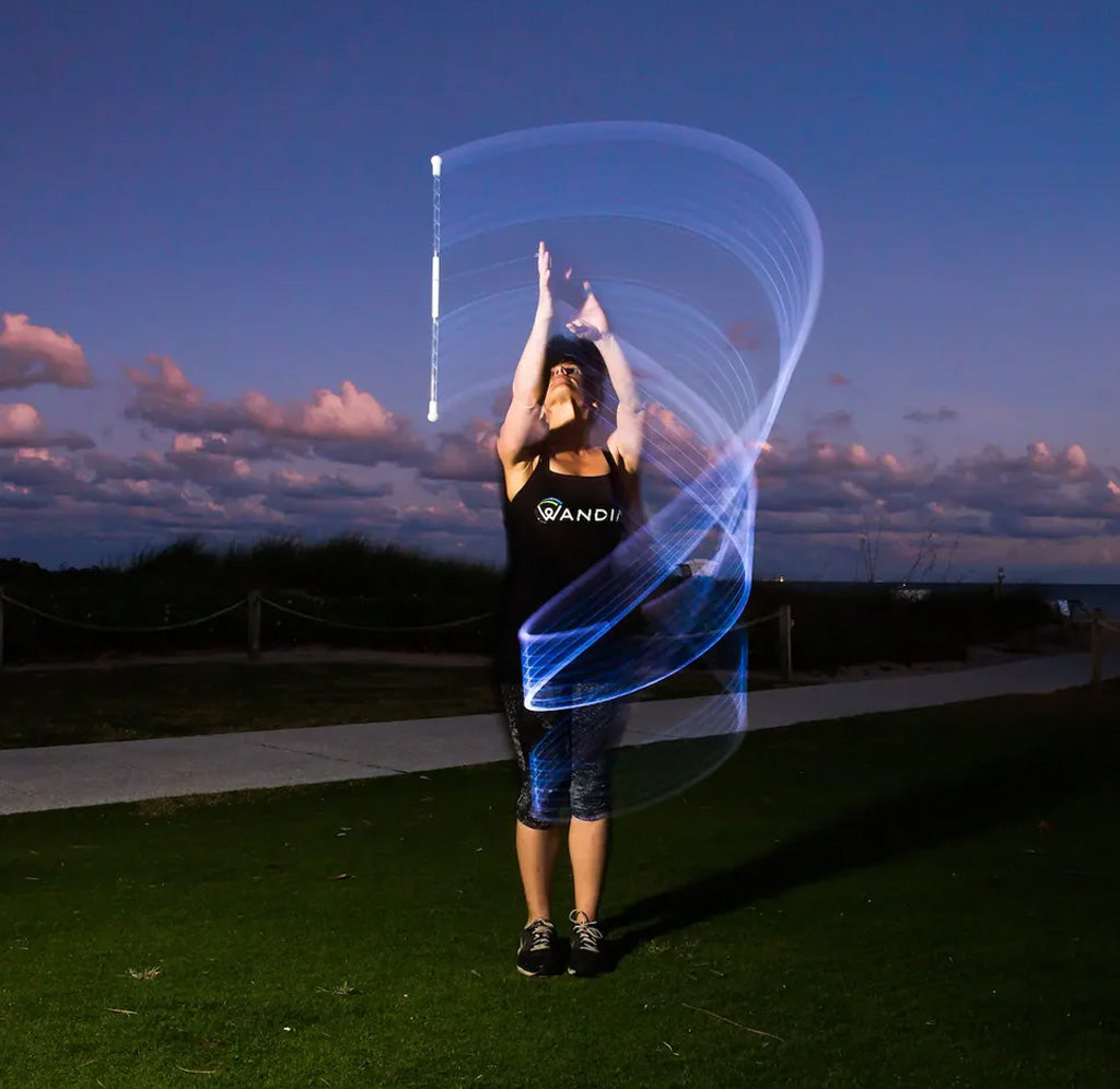 Person using a light wand with a blue light trail against a dark sky
