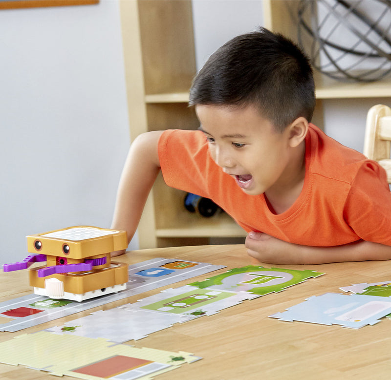 A child is laughing while playing with the robotic sandwich that is moving down a track.