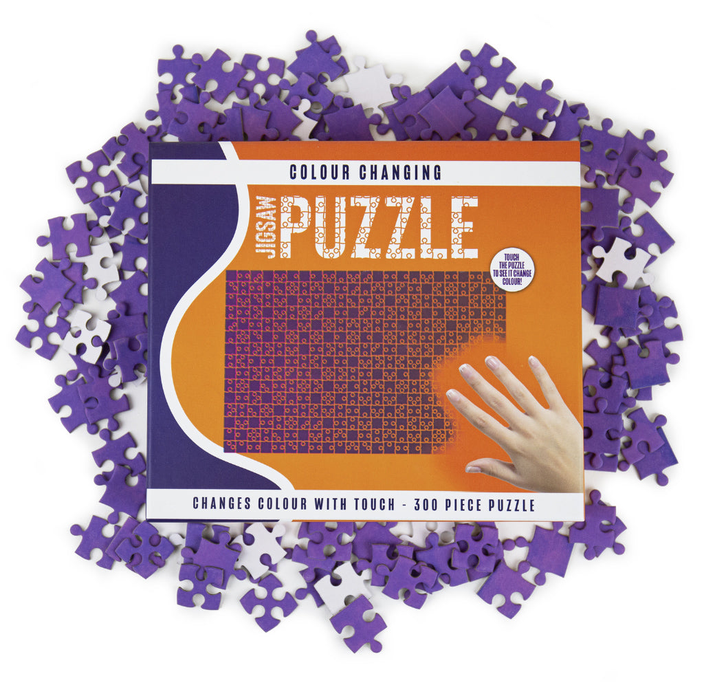 An image of the product box is orange and purple. Purple and white puzzle pieces are skewed around the box. A hand from the lower left is highlighted in pink to show the change with touch.