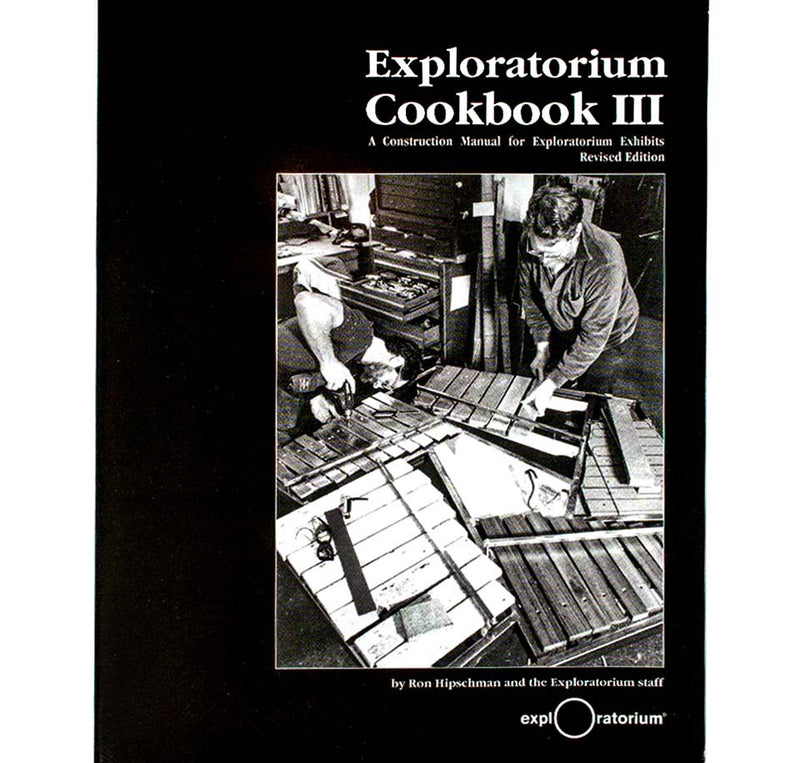 This softcover book is black with a black and white image of two men working with wood to create an exhibit for the Exploratorium.