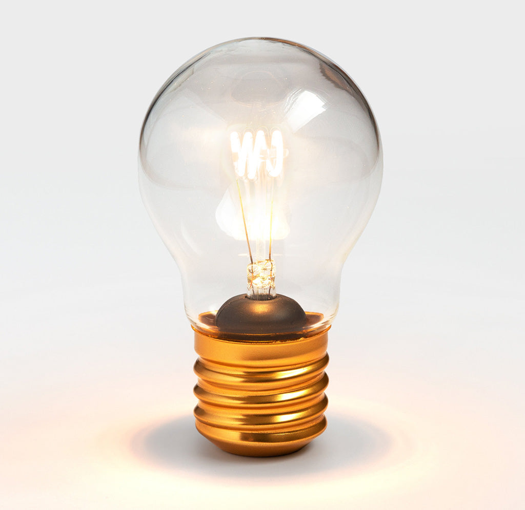 A glass light bulb is standing upright illuminated with an LED coil.