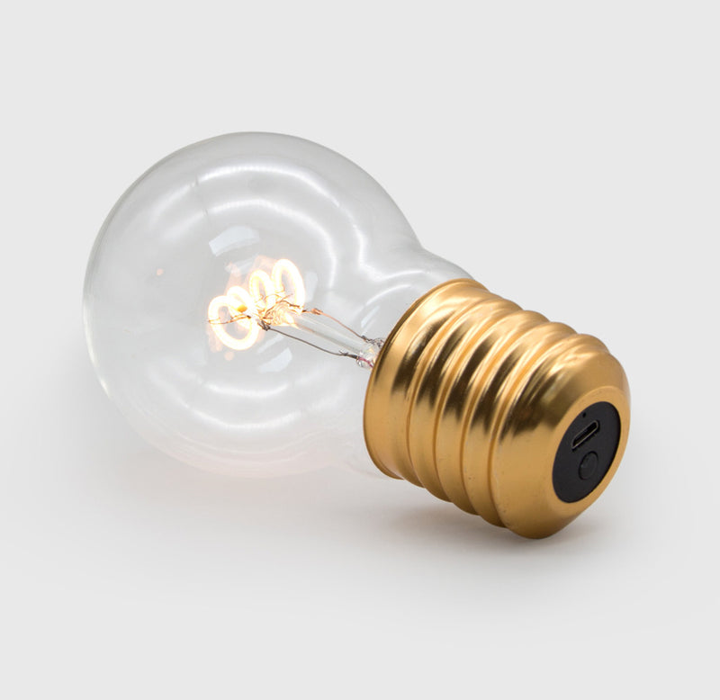 A glass light bulb illuminated with an LED coil lying on its side.