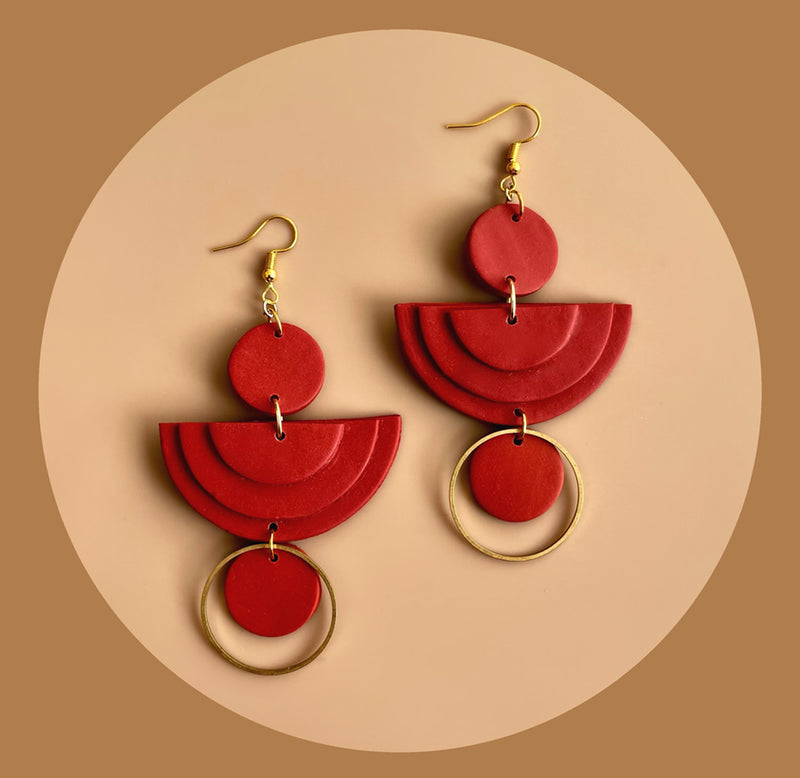 A set of two red & gold earrings made of geometric circles and crescents.
