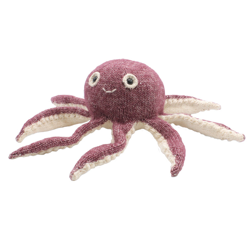 A magenta purple knitted octopus with cream white underneath, two eyes, and a mouth.