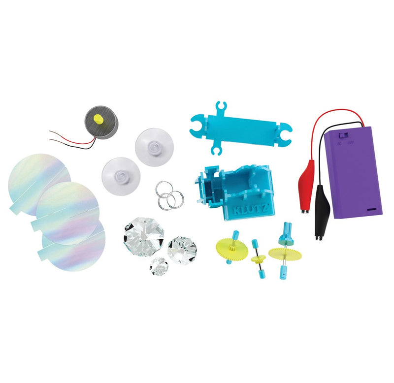 The 18 parts include 3 clear crystals, 3 silver rings, 2 suction cups, 3 holographic plastic pieces, a motor with wires, a battery box with alligator clips, and a plastic gearbox.