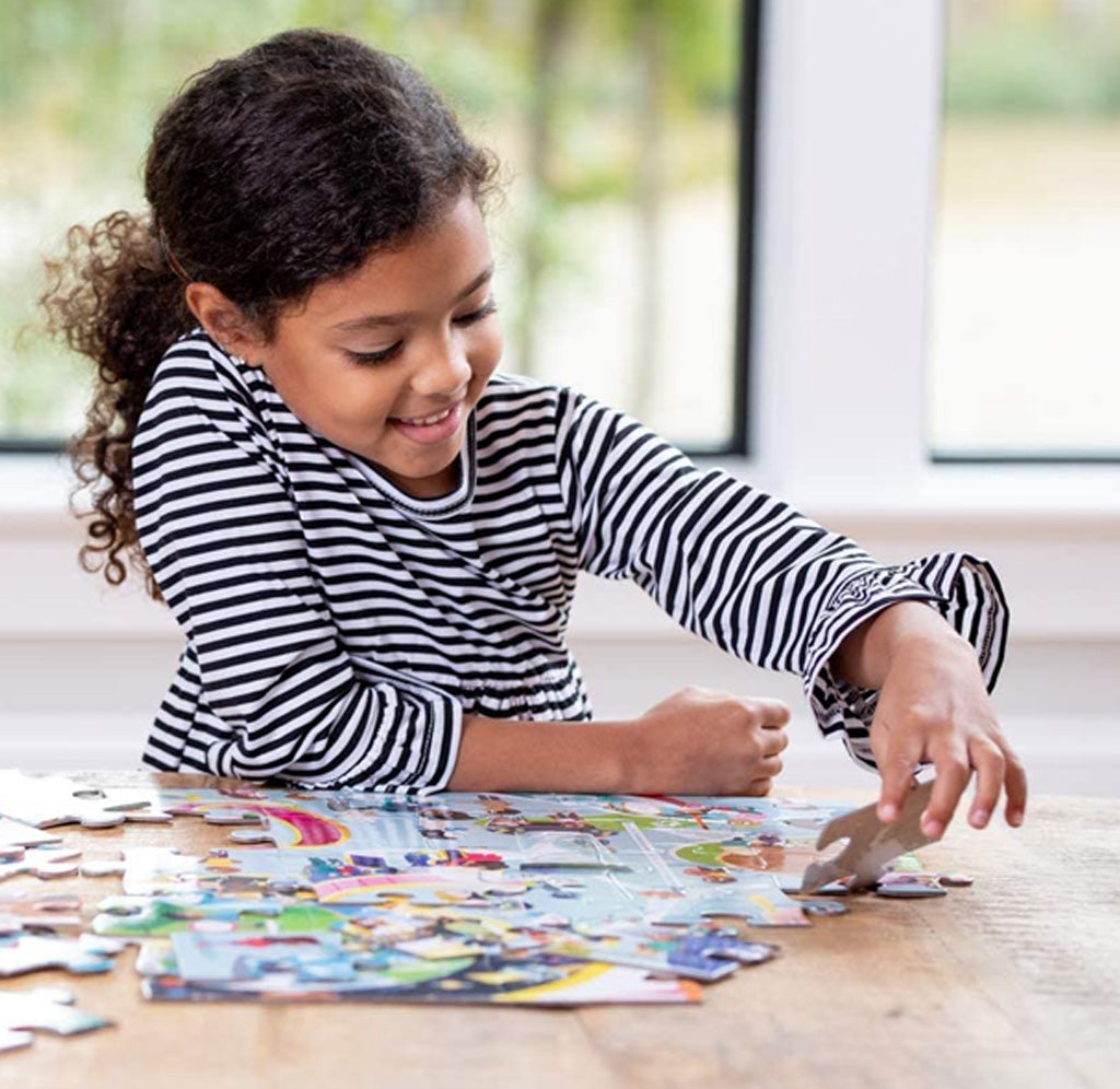 A young smiling child is putting the puzzle together on a table. 