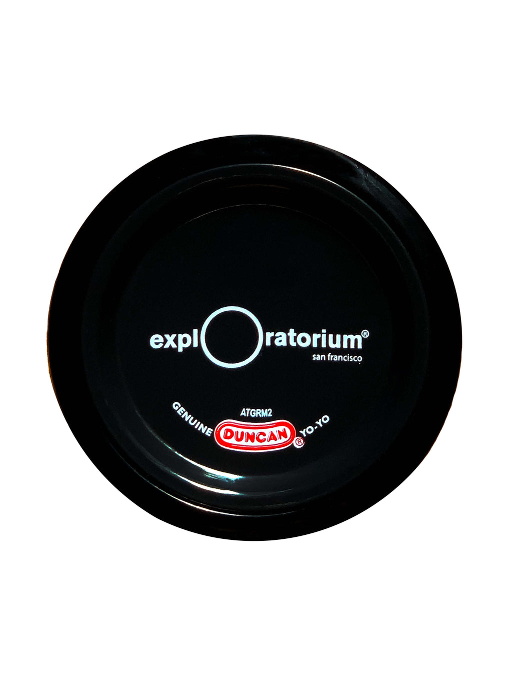 The opposite side of the black plastic yo-yo with the Exploratorium logo, San Francisco, in white across the middle and duncan in red.