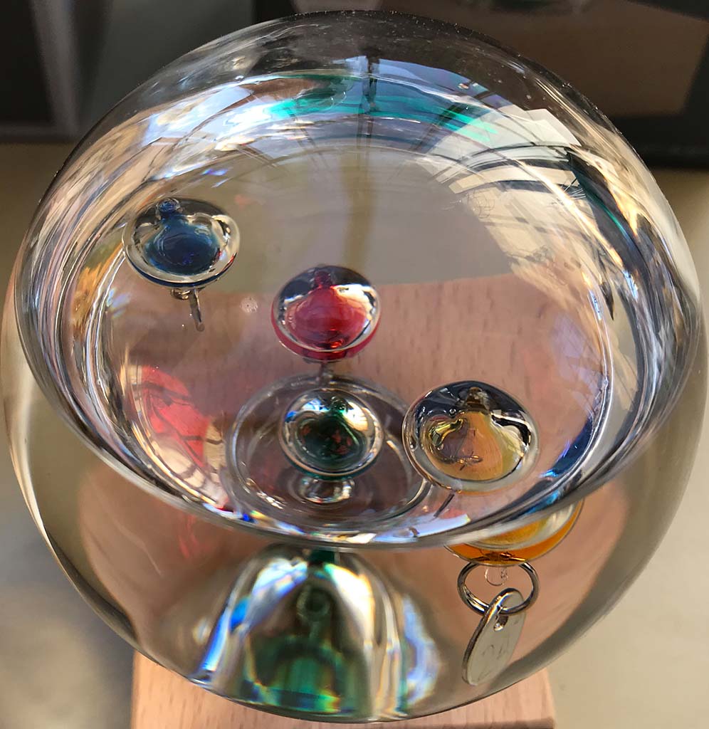 A close up image of the glass globe with the different glass liquid filled teardrops at different densities in the water