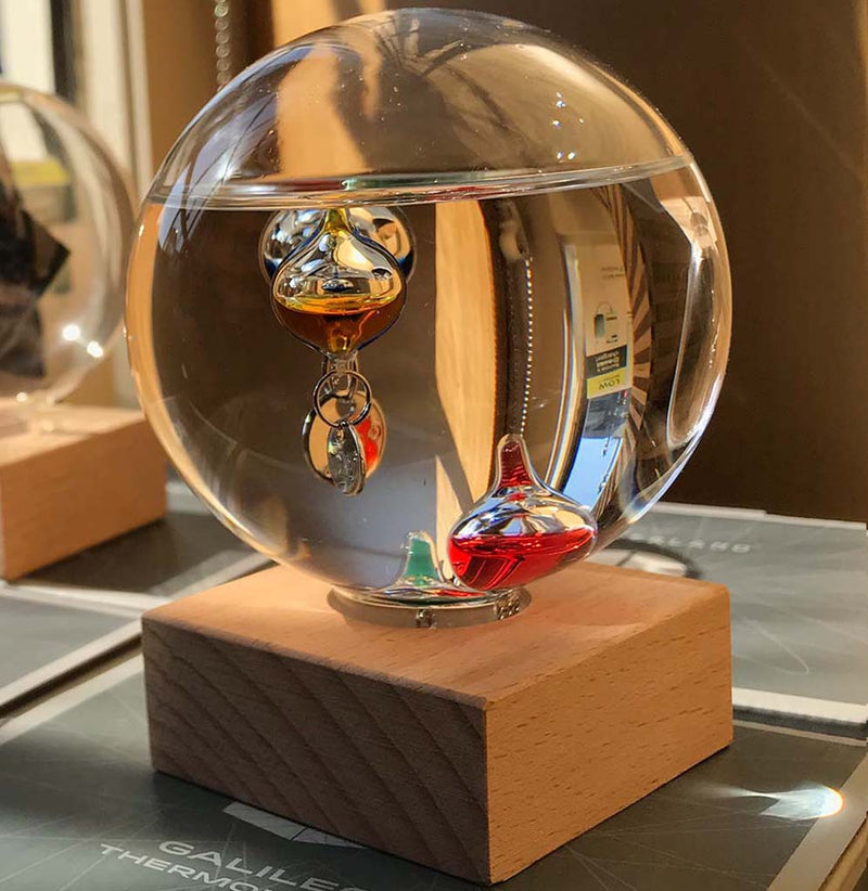The water-filled glass globe rests securely on a handsome wood base. 4" x 3" in diameter. The different glass liquid-filled teardrops at different densities in the water.
