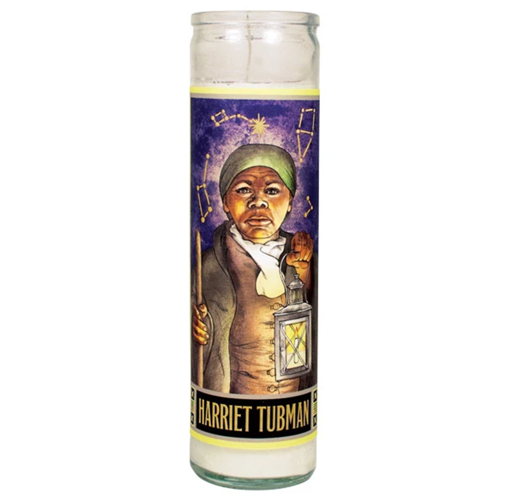 An 8-inch white candle with an illustrated image of Harriet Tubman on the front. She is holding a lighted lantern. There are constellations above her head, and her name appears at the bottom in yellow against a black background.