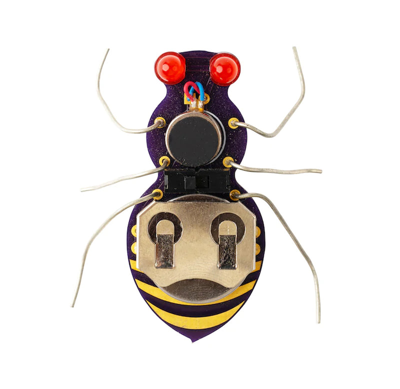 A black metal bug with yellow bumblebee strips at the bottom, two red LED lights for eyes, and six silver metal legs, a  gold coin cell battery holder on its back. 