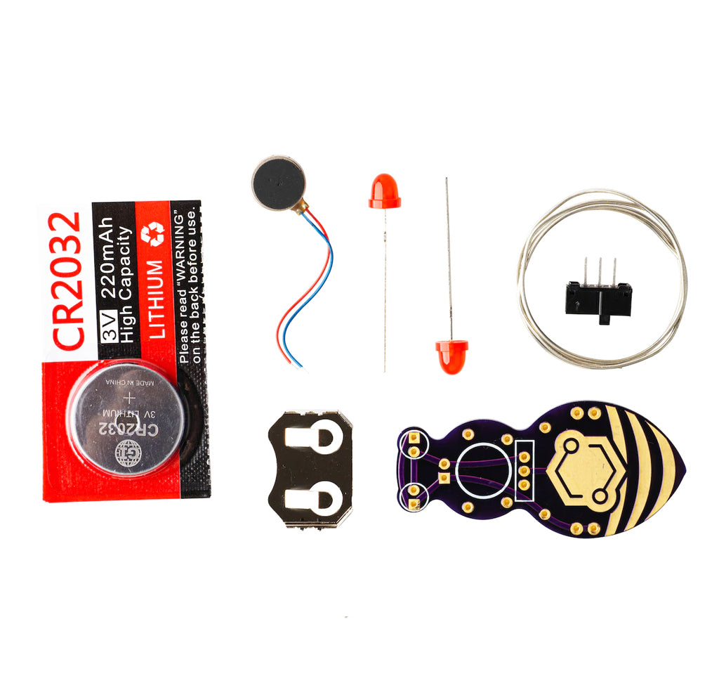 All the parts for the kit are laid out; there is a silver coin battery, a vibrating motor, two red LED lights, one vibrating motor, one switch, a circle of cut wire, a gold battery holder, and the black and yellow jitterbug board. 