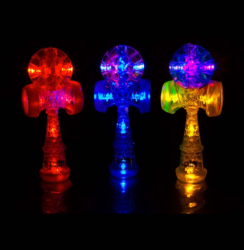 The red, blue, and yellow kendama's lit up against a dark background.