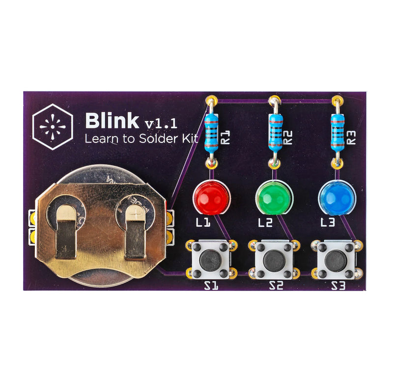 The Blink Solder kit has a black rectangular board with three blue resistors, one red LED, one green LED, one blue LED, three black and gray push buttons, and a gold coin cell holder.