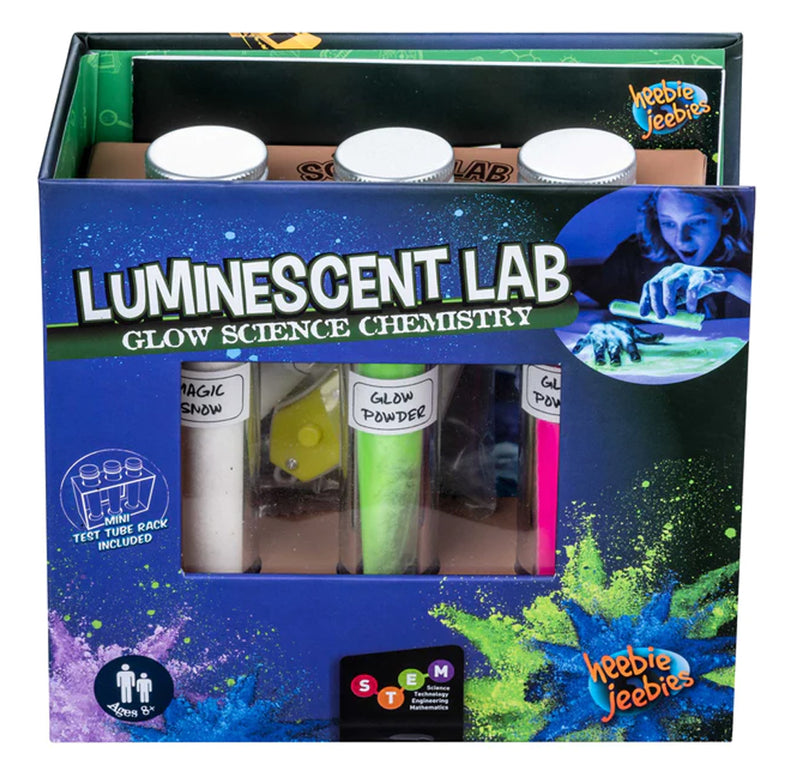 Three test tubes with white magic snow and green and pink glow powder sit within a dark blue box with a window cut out. Luminescent powders appear on the box.