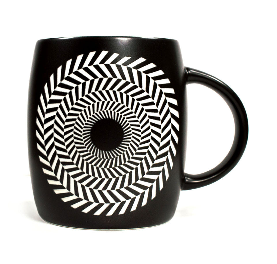 It is a black ceramic mug with a black and white circular optical illusion etched on the front.