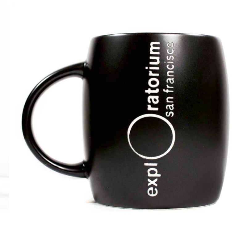It is a black ceramic mug with the Exploratorium logo, San Francisco, vertically etched in white.