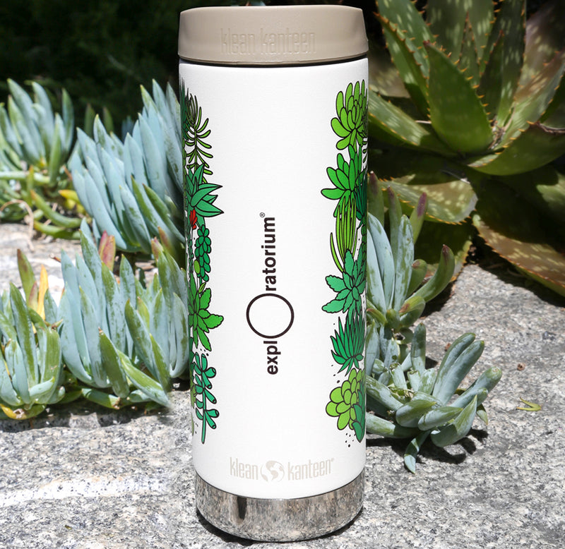 A tall, slender white water bottle with a beige lid, plants of many shades of green wrapped around the outside, and the Exploratorium logo in black down the middle.