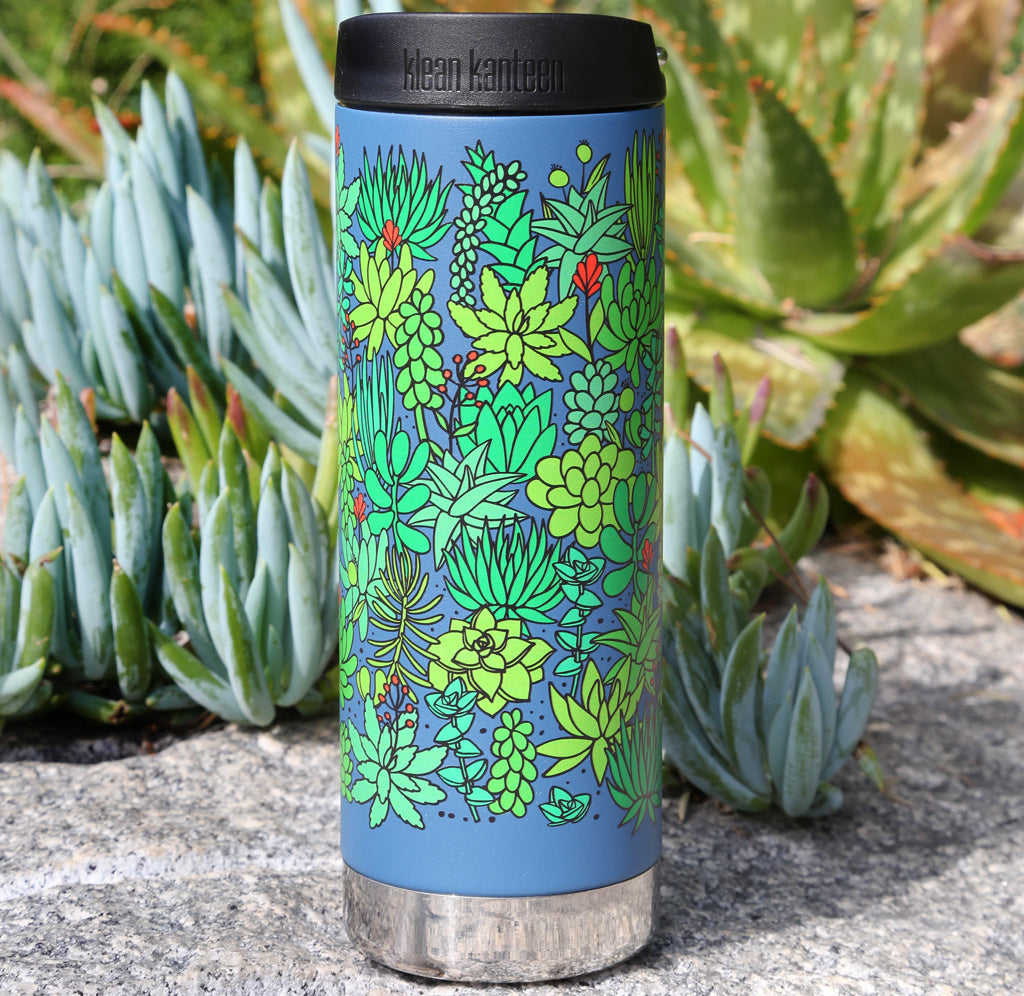 A tall, slender blue water bottle with a black lid and plants of many shades of green wrapped around the outside.