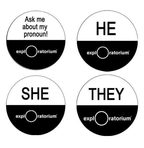 Four circular pins with half white with black text on the top with the pronouns and "Ask me about my pronoun!" The bottom half is black, with the Exploratorium in white text.