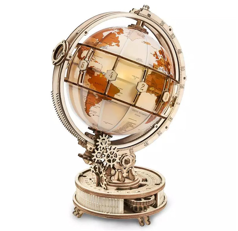 The Luminous Globe kit is put together with natural plywood. The base contains gears for the movement, and the globe is brown and white with a band in plywood for the time zones and an orbital magnifier on the left side.