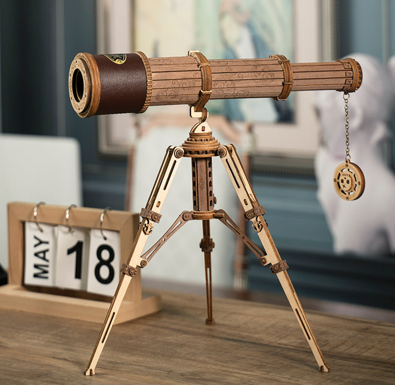 The brown monocular telescope is sitting on its tripod on a table to show scale and size.