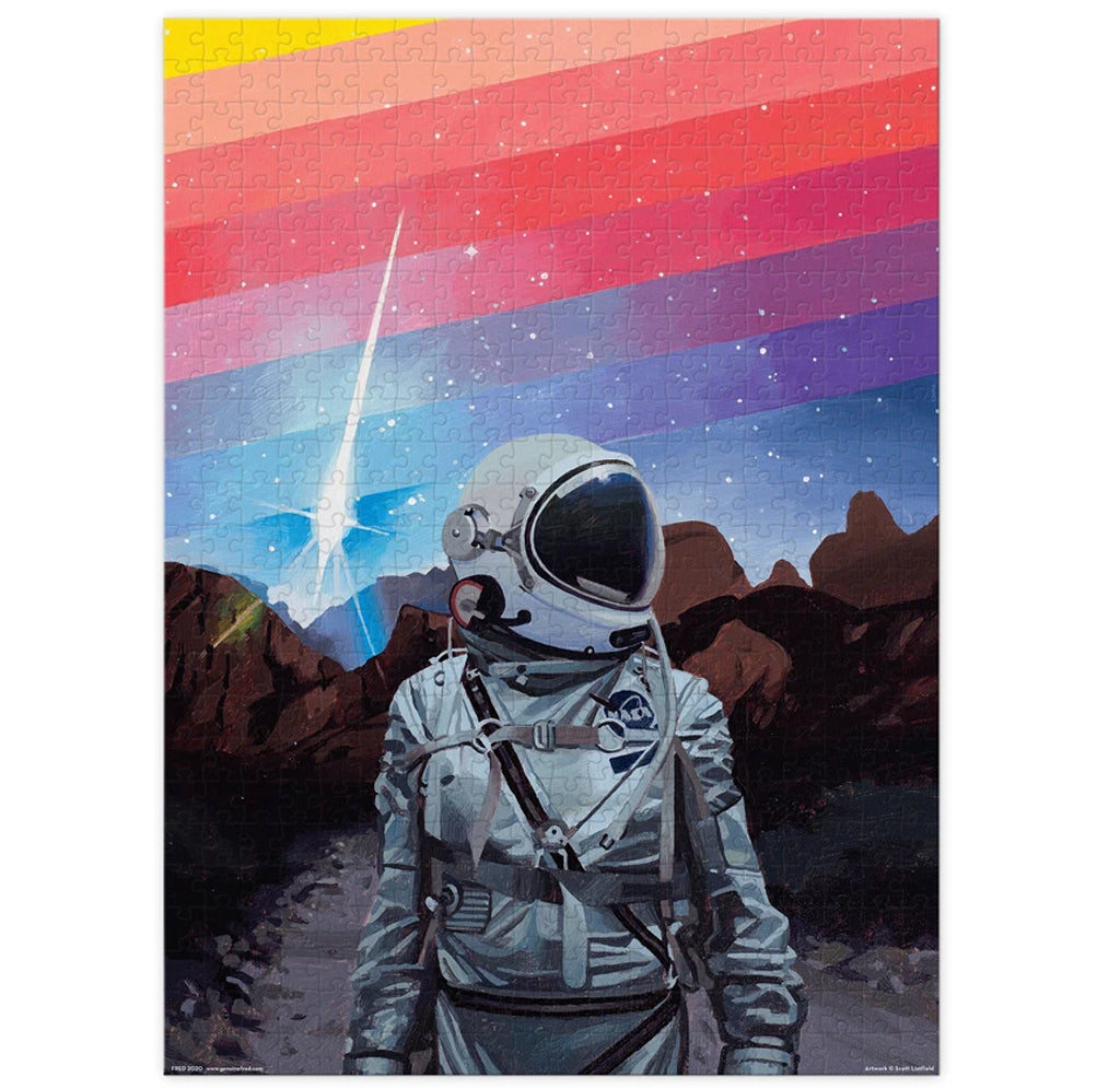 The puzzle illustrates an astronaut standing on a rocky planet's surface; there is a rainbow of colors of blues and reds behind in the starry sky.