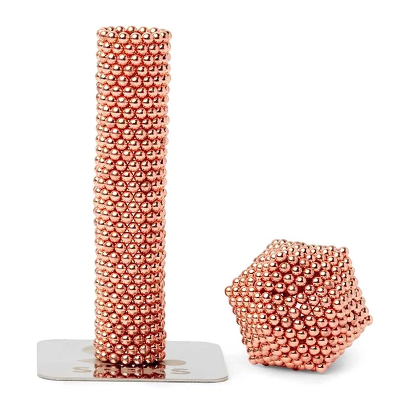 A cylindrical tube and small cube in the rose gold Luxe Speks.