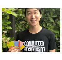 A young man is holding a set of the Sushi Go! cards in his hand and facing the camera.