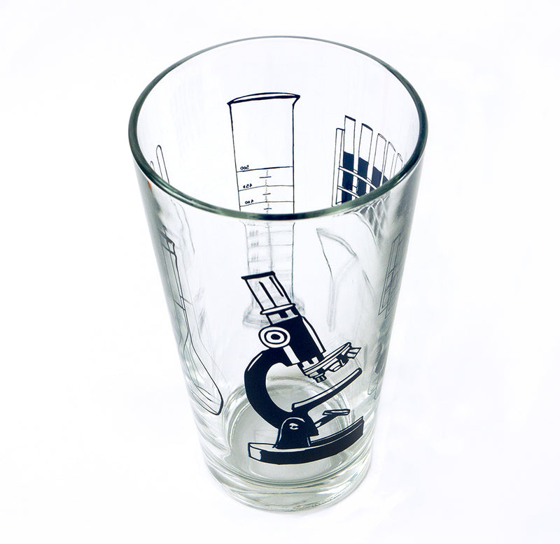 A 16oz clear pint glass with science tools in silhouette in navy ink.