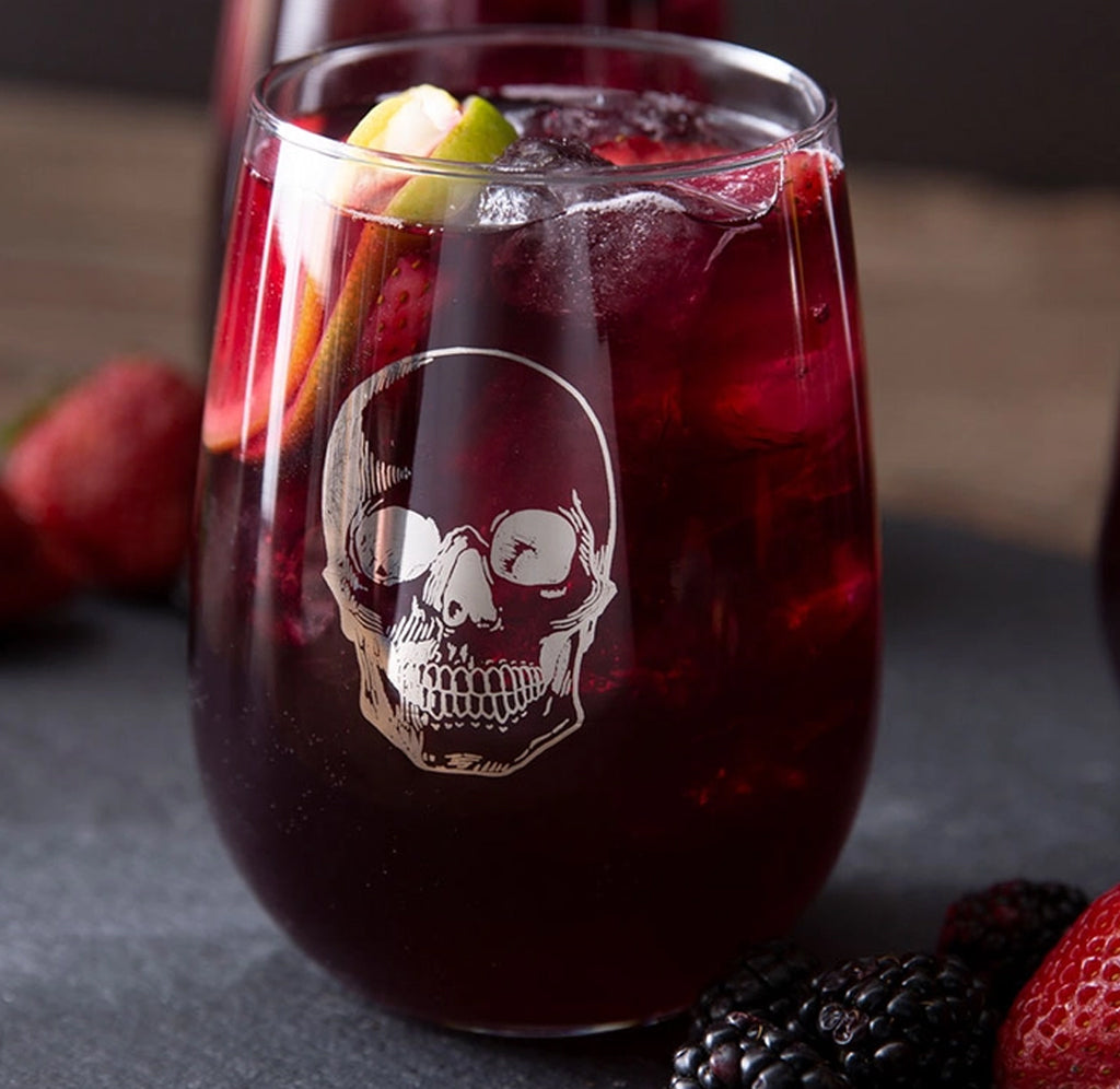 A stemless wine glass filled with red sangria; a silver human skull in metallic platinum ink on the front.