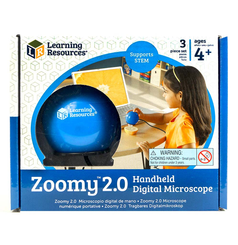 A young girl sitting at a table uses the Zoomy handheld digital microscope to look closer at a lemon. The magnified image of the lemon is on the screen of the child's laptop computer.